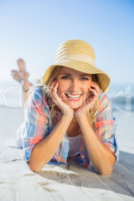 Pretty blonde smiling at camera at the beach lying on the sand