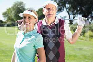 Golfing couple standing smiling at camera