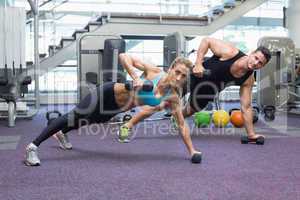 Bodybuilding man and woman holding dumbbells in plank position