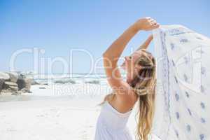 Pretty carefree blonde posing on the beach with scarf