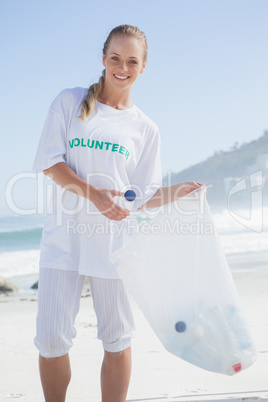 Blonde volunteer picking up trash on the beach