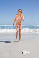Happy fit woman in bikini running from the sea