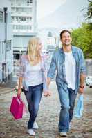 Hip young couple on shopping trip walking uphill