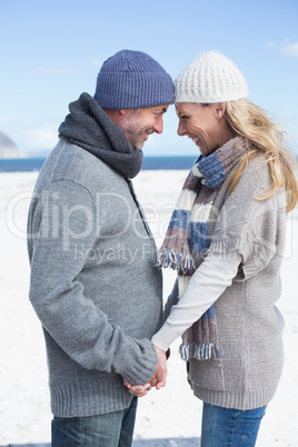 Smiling couple standing on the beach in warm clothing