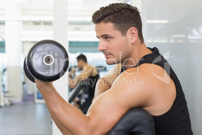 Focused bodybuilder lifting heavy black dumbbell