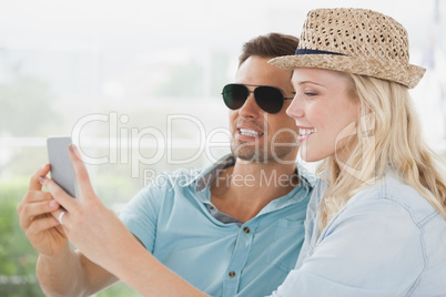 Cute couple sitting in cafe looking at smartphone