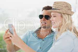 Cute couple sitting in cafe looking at smartphone