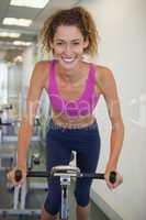 Pretty fit woman on the spin bike smiling at camera