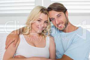 Cute casual couple sitting on couch smiling at camera