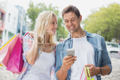 Hip young couple looking at smartphone on shopping trip