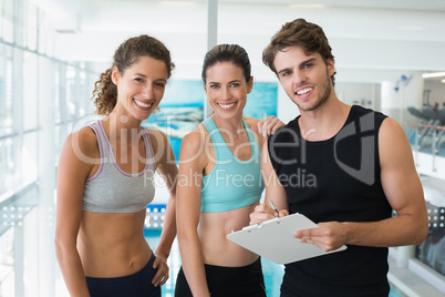 Fit women with trainer taking notes and smiling at camera