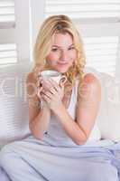 Happy blonde relaxing on the couch with coffee