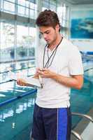 Swimming coach looking at his stopwatch by the pool