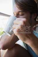 Handsome man sitting by the window having coffee