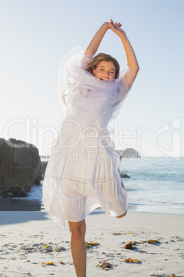 Beautiful happy blonde in white sundress and scarf on the beach