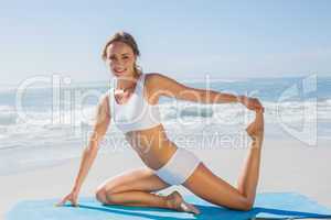 Gorgeous fit blonde in seated yoga pose on the beach
