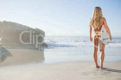 Gorgeous blonde surfer in bikini holding her board