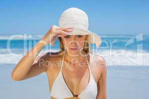 Smiling blonde in white bikini and sunhat on the beach