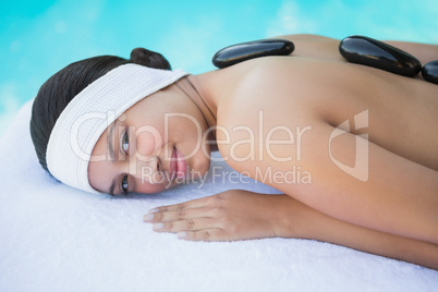 Smiling brunette lying on towel having a hot stone massage