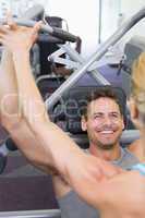 Personal trainer coaching bodybuilder using weight machine