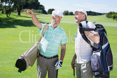 Golfer friends chatting and holding their golf bags