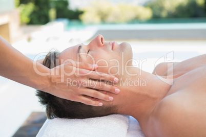 Peaceful man getting a head massage poolside