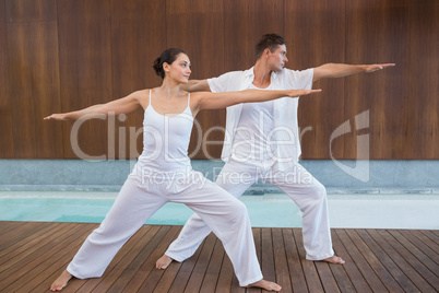 Peaceful couple in white doing yoga together in warrior position