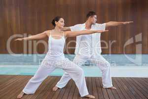 Peaceful couple in white doing yoga together in warrior position