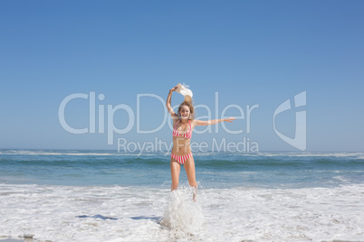 Gorgeous fit woman in striped bikini and sunhat jumping at beach