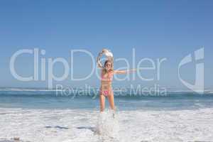 Gorgeous fit woman in striped bikini and sunhat jumping at beach
