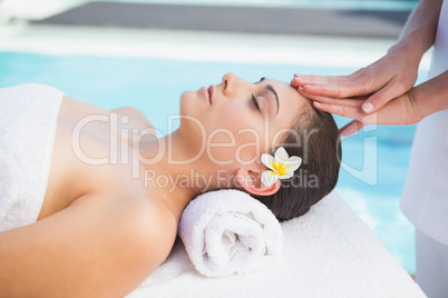 Tranquil brunette getting a head massage poolside