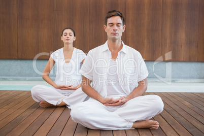 Peaceful couple in white sitting in lotus pose together