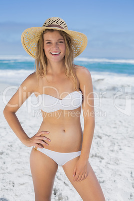 Beautiful happy blonde on the beach in white bikini and sunhat