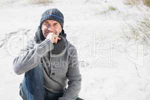 Attractive man thinking on the beach in hat and scarf