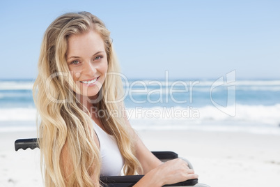 Wheelchair bound blonde smiling at the camera on the beach