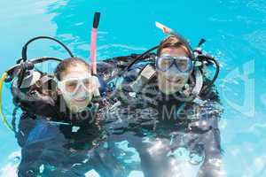 Smiling couple on scuba training in swimming pool looking at cam