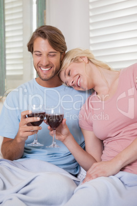 Happy couple sitting on couch with red wine