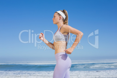 Sporty focused blonde jogging on the beach