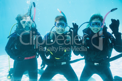 Friends on scuba training submerged in swimming pool making ok s