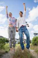 Smiling couple leaping outside together in their garden