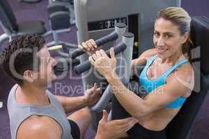 Personal trainer coaching smiling female bodybuilder using weigh