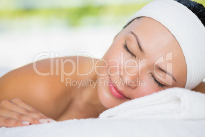 Smiling brunette lying on massage table with eyes closed