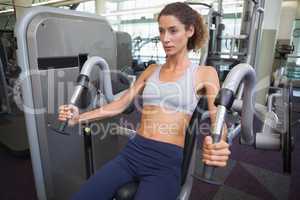 Fit woman using the weights machine for her arms