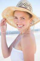 Pretty smiling blonde on the beach wearing straw hat