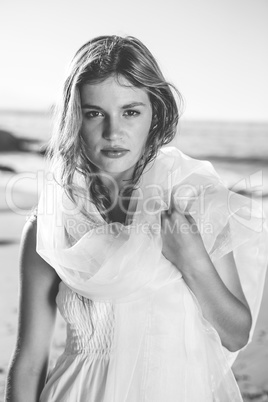 Beautiful blonde in white sundress and scarf on the beach