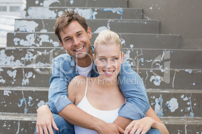 Hip young couple sitting on steps smiling at camera