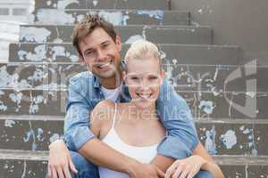 Hip young couple sitting on steps smiling at camera