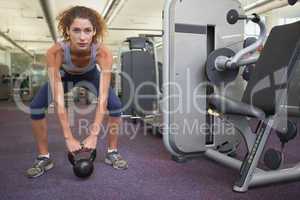 Fit woman squatting with kettlebell