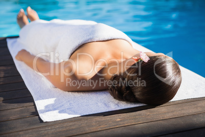 Relaxed brunette lying on a towel poolside Relaxed brunette lying on a towel poolside
