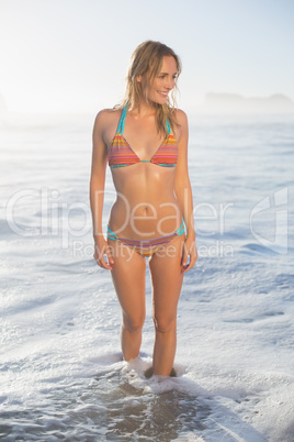 Happy blonde standing by the sea posing in bikini